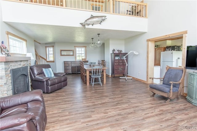 1812 Grenadier Island Rd Unit 1, Cape Vincent, NY 13618 - living area featuring wood finished floors, a stone fireplace, a towering ceiling, a chandelier, and stairway
