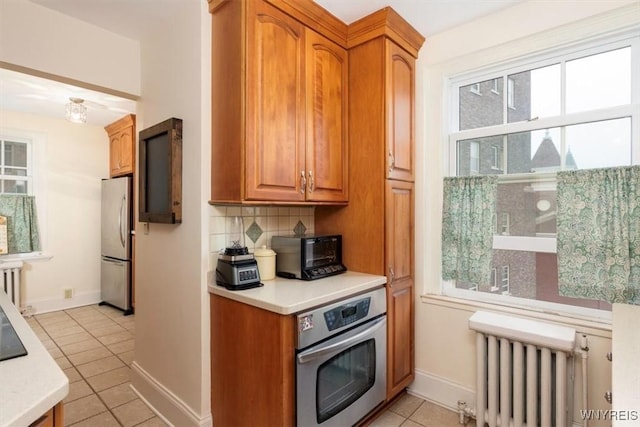 83 Bryant # 7Ab, Buffalo, NY 14209 - kitchen featuring stainless steel appliances, radiator, light tile patterned flooring, light countertops, and tasteful backsplash