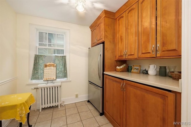 83 Bryant # 7Ab, Buffalo, NY 14209 - kitchen with radiator, freestanding refrigerator, brown cabinets, light countertops, and light tile patterned floors