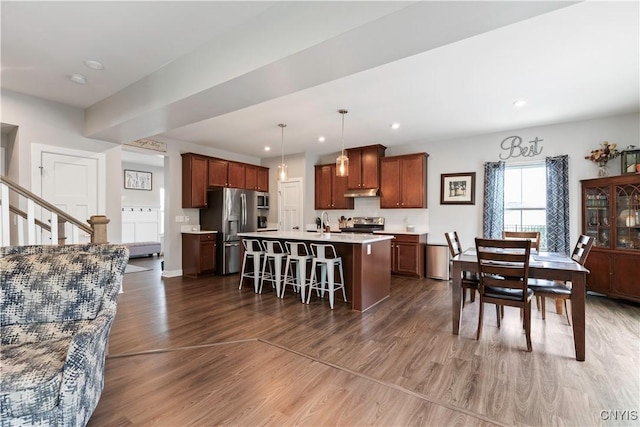 2600 Sunshine Cir, Camillus, NY 13031 - kitchen featuring stainless steel appliances, dark wood finished floors, light countertops, a breakfast bar area, and a center island with sink