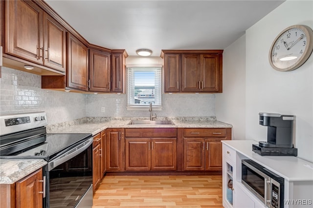445 75th St, Niagara Falls, NY 14304 - kitchen with appliances with stainless steel finishes, light wood finished floors, tasteful backsplash, and brown cabinetry