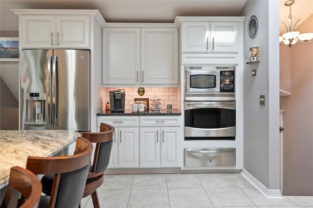 798 Hawthorne Pl, Webster, NY 14580 - kitchen featuring stainless steel appliances, a warming drawer, light stone countertops, decorative backsplash, and light tile patterned floors