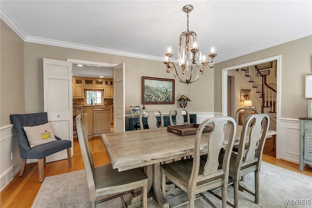 29 Cherry Tree Ln, Orchard Park, NY 14127 - dining space featuring crown molding, a chandelier, light wood finished floors, stairs, and a wainscoted wall