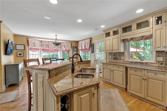 29 Cherry Tree Ln, Orchard Park, NY 14127 - kitchen featuring cream cabinets, a breakfast bar, ornamental molding, an island with sink, and tasteful backsplash