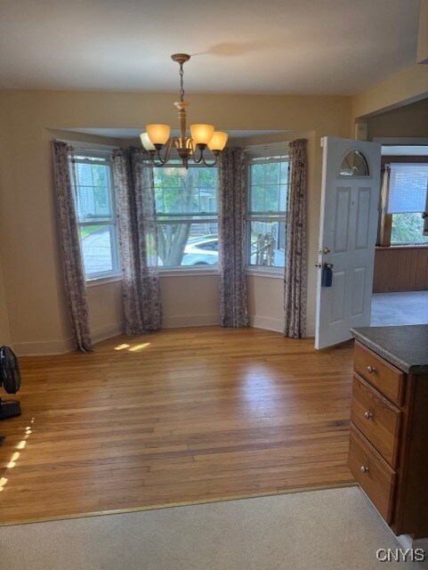 308 Wayland Rd, Salina, NY 13208 - unfurnished dining area with light wood-style floors, plenty of natural light, and a chandelier