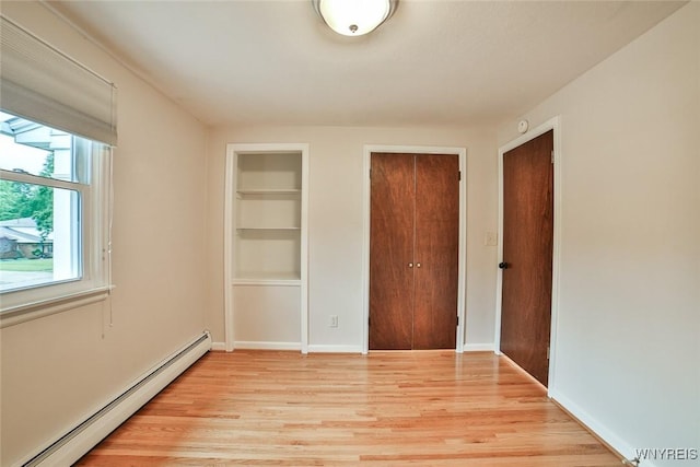 46 Macarthur Dr, Amherst, NY 14221 - unfurnished bedroom featuring a baseboard heating unit, light wood-style flooring, and multiple closets