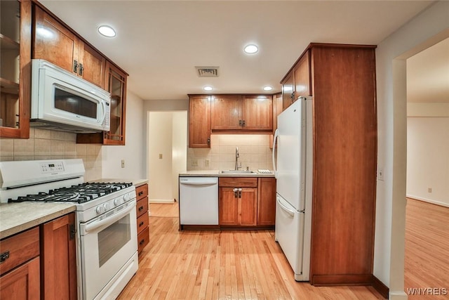 46 Macarthur Dr, Amherst, NY 14221 - kitchen featuring white appliances, light wood finished floors, decorative backsplash, brown cabinetry, and light countertops