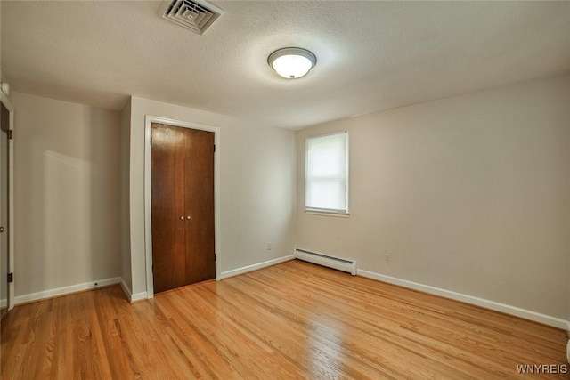 46 Macarthur Dr, Amherst, NY 14221 - unfurnished bedroom with a baseboard heating unit, light wood-type flooring, a closet, and a textured ceiling
