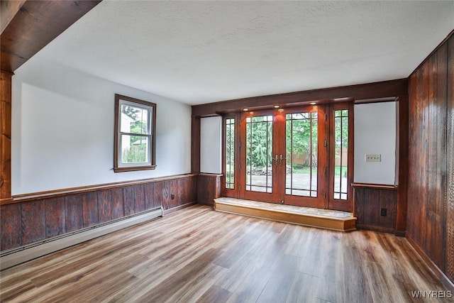 46 Macarthur Dr, Amherst, NY 14221 - empty room featuring a baseboard heating unit, wooden walls, wood finished floors, wainscoting, and baseboard heating