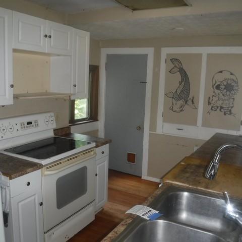 13 E Albion St, Murray, NY 14470 - kitchen with white range with electric stovetop, white cabinets, and wood finished floors