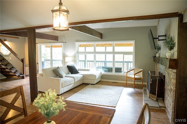 1346 Otisco Valley Rd, Otisco, NY 13110 - living area featuring plenty of natural light, a stone fireplace, stairs, wood finished floors, and beamed ceiling