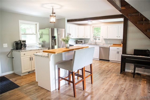 1346 Otisco Valley Rd, Otisco, NY 13110 - kitchen with appliances with stainless steel finishes, white cabinetry, light wood-type flooring, a breakfast bar area, and a center island