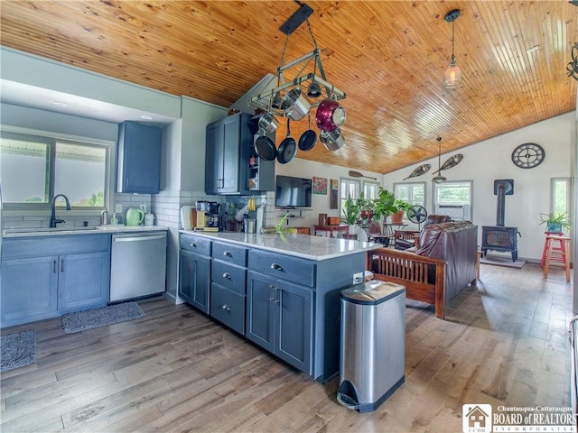 8800 Harmon Hill Rd, Pomfret, NY 14063 - kitchen with stainless steel dishwasher, a peninsula, a wood stove, blue cabinets, and lofted ceiling