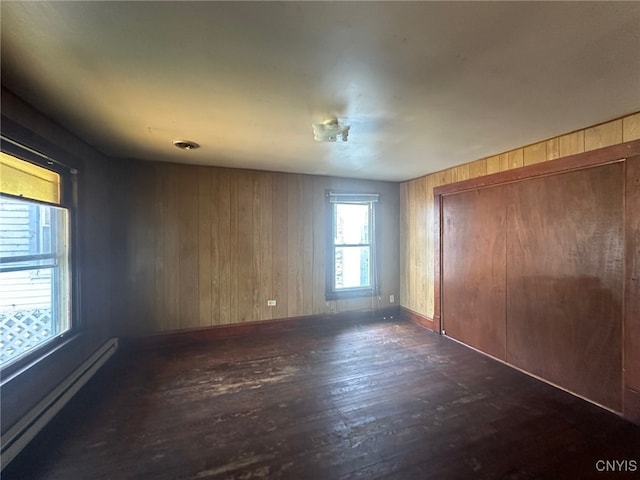 85 W Clark St, German Flatts, NY 13357 - unfurnished bedroom featuring a baseboard heating unit, dark wood-type flooring, wooden walls, and a closet