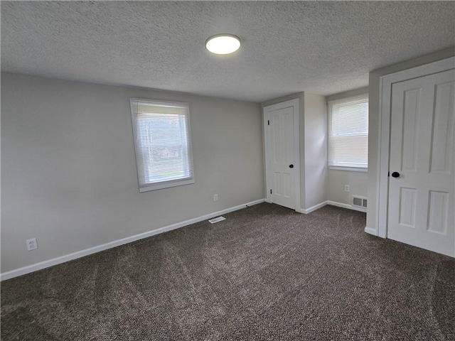 2381 Culver Rd, Irondequoit, NY 14609 - unfurnished bedroom featuring dark colored carpet, a textured ceiling, and multiple closets