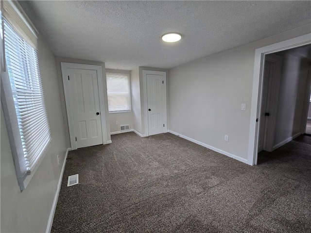 2381 Culver Rd, Irondequoit, NY 14609 - unfurnished bedroom with a textured ceiling, dark colored carpet, and multiple windows