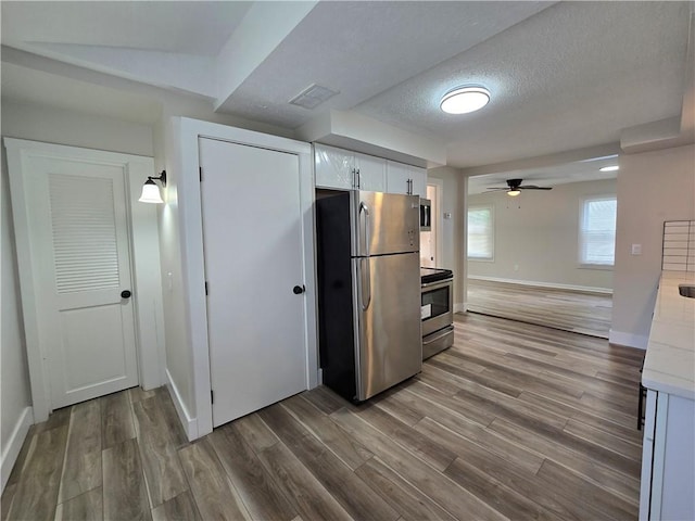 2381 Culver Rd, Irondequoit, NY 14609 - kitchen featuring appliances with stainless steel finishes, white cabinetry, wood finished floors, light countertops, and a textured ceiling