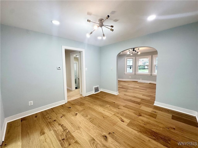 1433 Eggert Rd, Amherst, NY 14226 - unfurnished room with arched walkways, light wood finished floors, a chandelier, and recessed lighting
