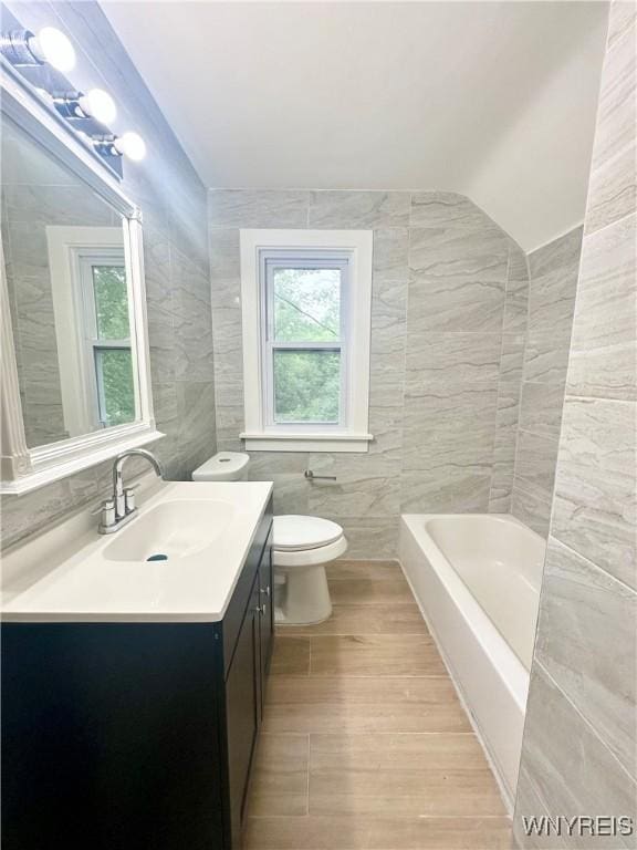1433 Eggert Rd, Amherst, NY 14226 - full bathroom with tile walls, vanity, a bathtub, and wood finished floors