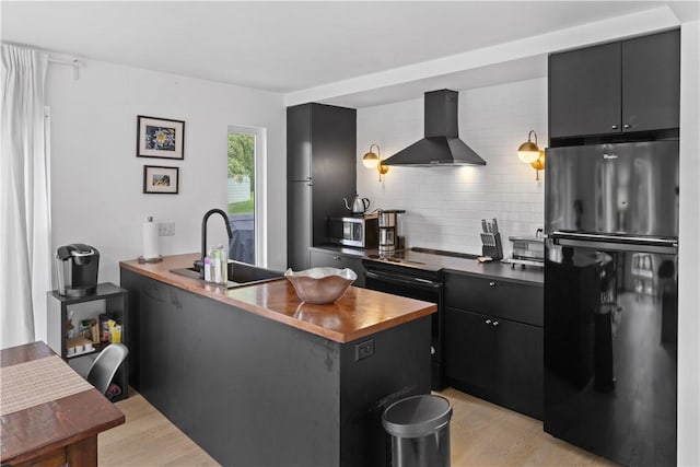 2064 County Highway 8, Roxbury, NY 12421 - kitchen featuring wall chimney exhaust hood, freestanding refrigerator, dark cabinets, decorative backsplash, and light wood-type flooring