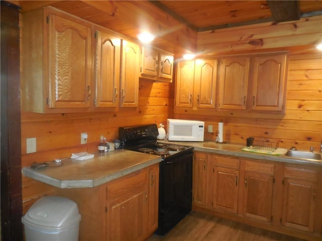 45 Olin Ave, Perry, NY 14530 - kitchen with black range with electric cooktop, white microwave, wood walls, light wood finished floors, and light countertops