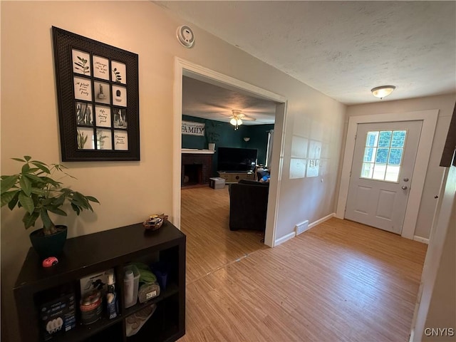 35381 State Route 3, Wilna, NY 13619 - foyer with wood finished floors, a textured ceiling, a brick fireplace, and ceiling fan