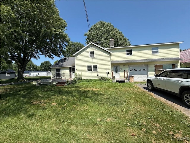 352 S Real St, Cape Vincent, NY 13618 - back of house with a lawn, asphalt driveway, an attached garage, and a chimney