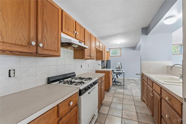 6924 Todd Way, Salina, NY 13088 - kitchen with white gas range, under cabinet range hood, decorative backsplash, brown cabinets, and light countertops