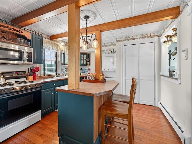 5631 W Blf, Newfane, NY 14126 - kitchen featuring gas stove, stainless steel microwave, baseboard heating, stacked washer / dryer, and blue cabinetry