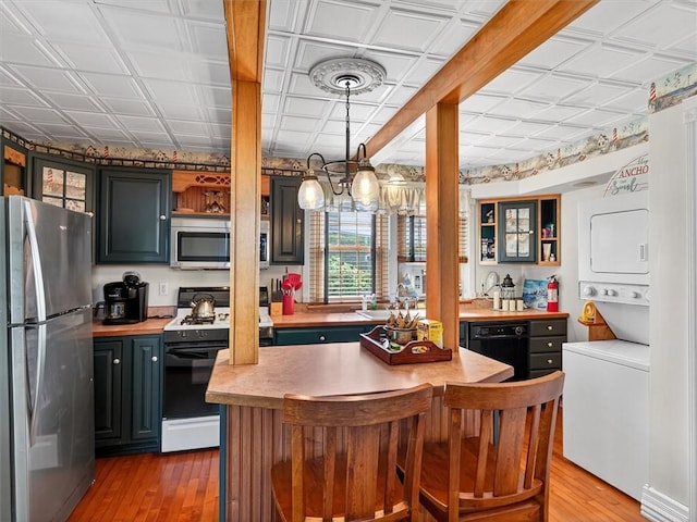 5631 W Blf, Newfane, NY 14126 - kitchen with appliances with stainless steel finishes, an ornate ceiling, stacked washer / drying machine, wood finished floors, and light countertops