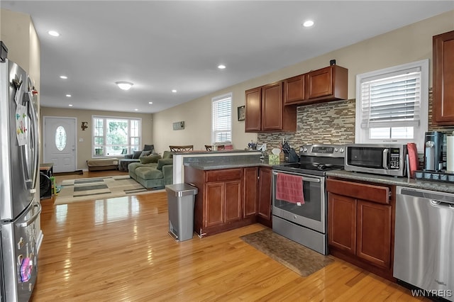1007 87th St, Niagara Falls, NY 14304 - kitchen featuring stainless steel appliances, open floor plan, dark countertops, light wood-style flooring, and a peninsula