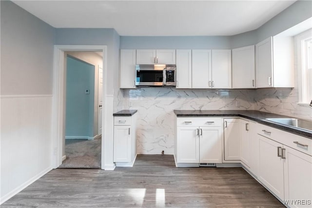 539 Windermere Blvd, Amherst, NY 14226 - kitchen featuring stainless steel microwave, wood finished floors, dark countertops, tasteful backsplash, and white cabinetry