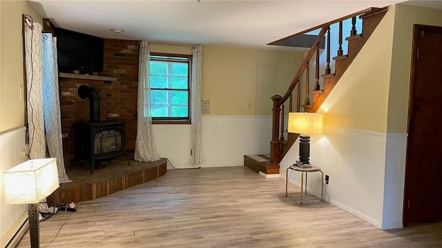 1221 Garden Ln, Middlesex, NY 14507 - unfurnished living room featuring a wainscoted wall, wood finished floors, stairway, and a wood stove
