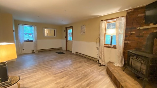 1221 Garden Ln, Middlesex, NY 14507 - unfurnished living room with a wood stove, a baseboard heating unit, light wood-type flooring, and healthy amount of natural light
