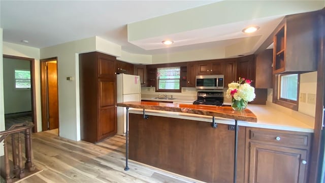 1221 Garden Ln, Middlesex, NY 14507 - kitchen with stainless steel microwave, range, a peninsula, light wood-style floors, and glass insert cabinets