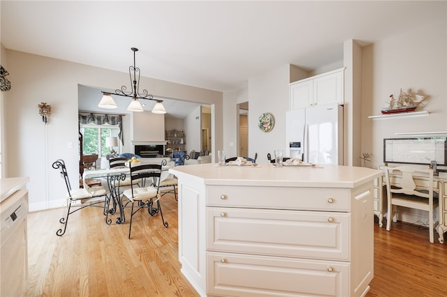 10 Bristol View Dr, Perinton, NY 14450 - kitchen with white refrigerator with ice dispenser, light wood-style flooring, a glass covered fireplace, white cabinets, and light countertops