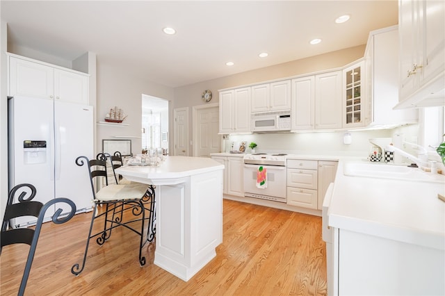 10 Bristol View Dr, Perinton, NY 14450 - kitchen featuring white appliances, a breakfast bar area, light wood-style floors, a kitchen island, and white cabinetry