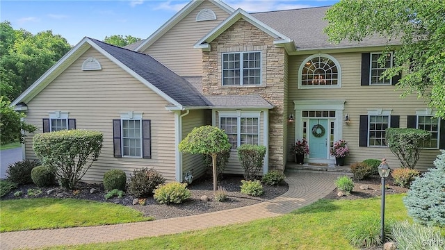 1002 Oreste St, Camillus, NY 13031 - traditional-style home with stone siding, a front yard, and roof with shingles