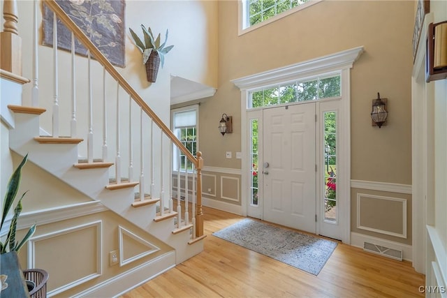 1002 Oreste St, Camillus, NY 13031 - entryway featuring a decorative wall, wainscoting, stairway, wood finished floors, and a towering ceiling