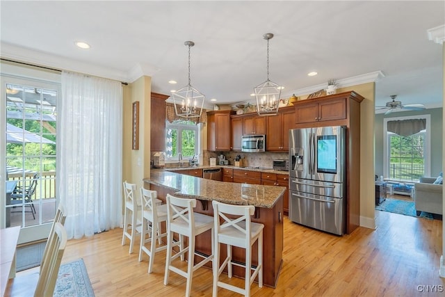 1002 Oreste St, Camillus, NY 13031 - kitchen with appliances with stainless steel finishes, light stone counters, brown cabinets, a chandelier, and backsplash