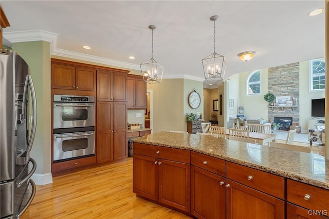 1002 Oreste St, Camillus, NY 13031 - kitchen with appliances with stainless steel finishes, a chandelier, light wood-style flooring, pendant lighting, and light stone countertops