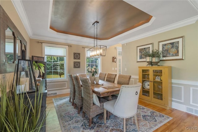 1002 Oreste St, Camillus, NY 13031 - dining area featuring a raised ceiling, a chandelier, light wood finished floors, a decorative wall, and crown molding