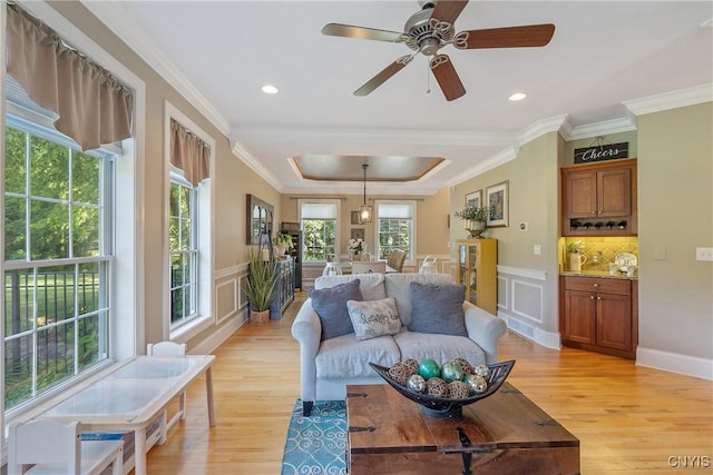 1002 Oreste St, Camillus, NY 13031 - living room featuring light wood-style flooring, a tray ceiling, crown molding, a decorative wall, and a wainscoted wall