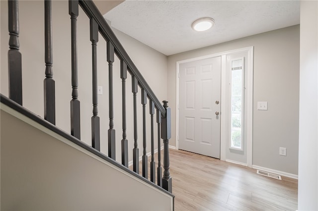 134 Jordache Ln, Ogden, NY 14559 - foyer with light wood-style floors, stairs, and a textured ceiling