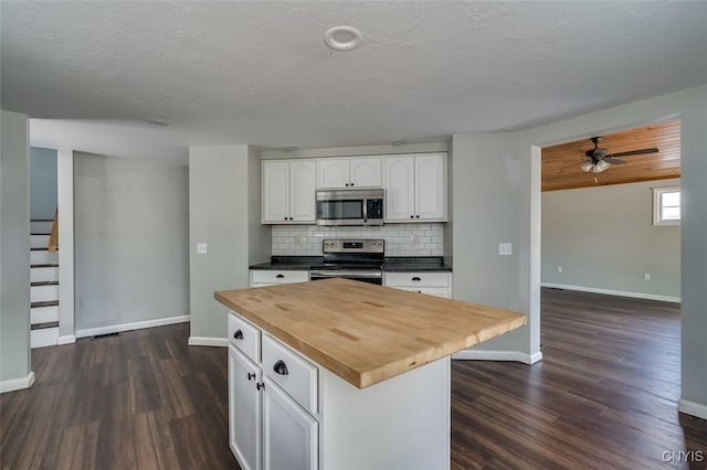 15243 Factory St, Clayton, NY 13632 - kitchen with stainless steel appliances, wooden counters, dark wood finished floors, white cabinetry, and a ceiling fan