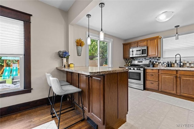 144 Whitfield Ave, Buffalo, NY 14220 - kitchen with stainless steel appliances, brown cabinets, a peninsula, and pendant lighting