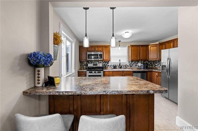 144 Whitfield Ave, Buffalo, NY 14220 - kitchen with appliances with stainless steel finishes, a peninsula, backsplash, hanging light fixtures, and a kitchen bar