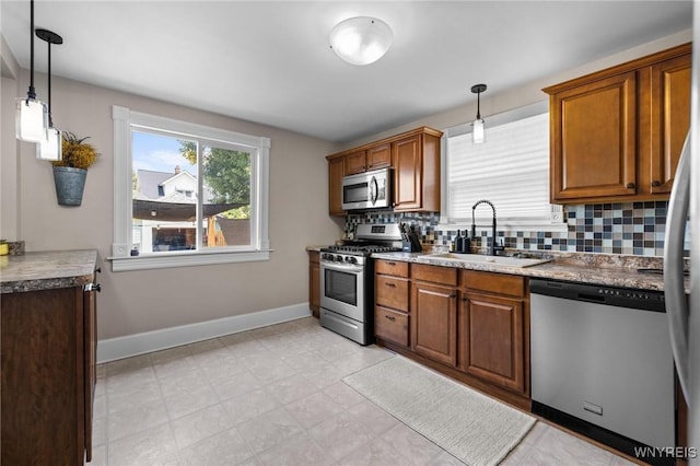 144 Whitfield Ave, Buffalo, NY 14220 - kitchen featuring appliances with stainless steel finishes, backsplash, hanging light fixtures, and brown cabinets