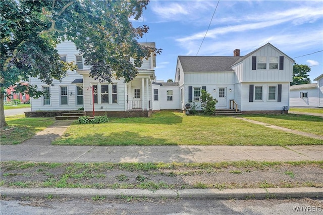10470 Main St, North Collins, NY 14111 - colonial house featuring board and batten siding, a front lawn, and a chimney