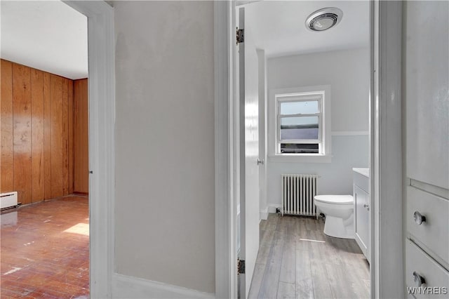 10470 Main St, North Collins, NY 14111 - bathroom featuring radiator, hardwood / wood-style floors, vanity, and wood walls